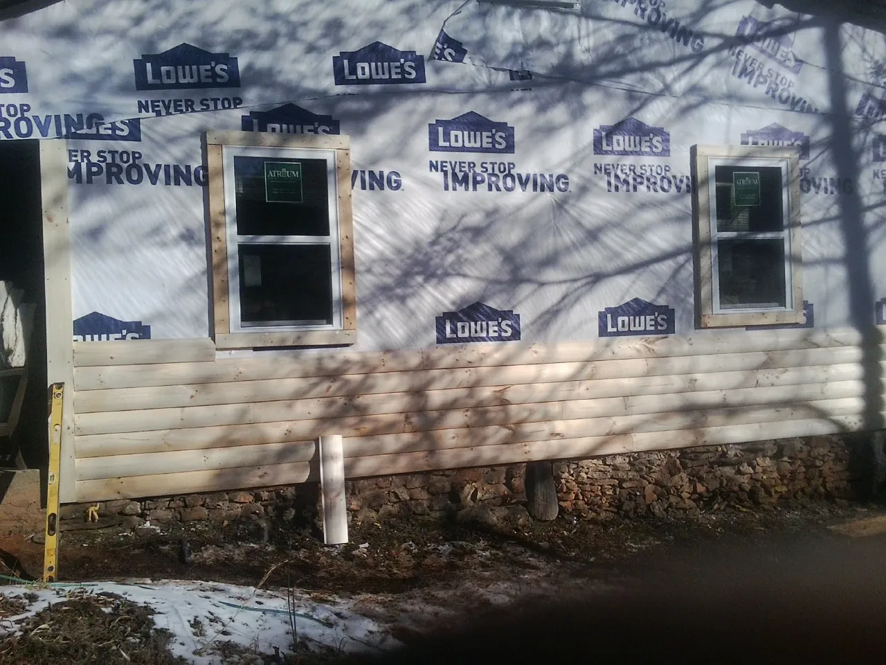 House wrap and new log siding going up on an exterior wall in Derby