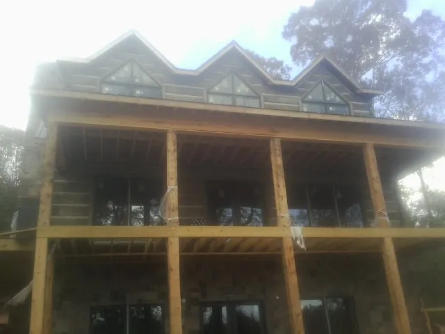 Dormers and porch framing on a large log home under construction — Roof Coating work by our crew in Derby